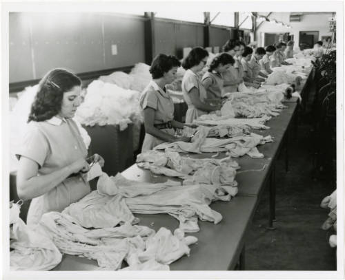 	
Black-and-white photograph of unidentified employees working at tables inside of the Signal Knitting Mills.