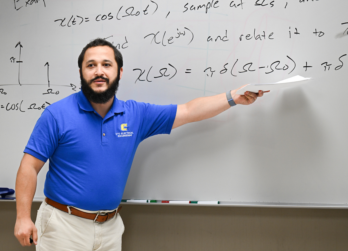Joshua Tyler stands in front of a greaseboard in his electrical engineering class