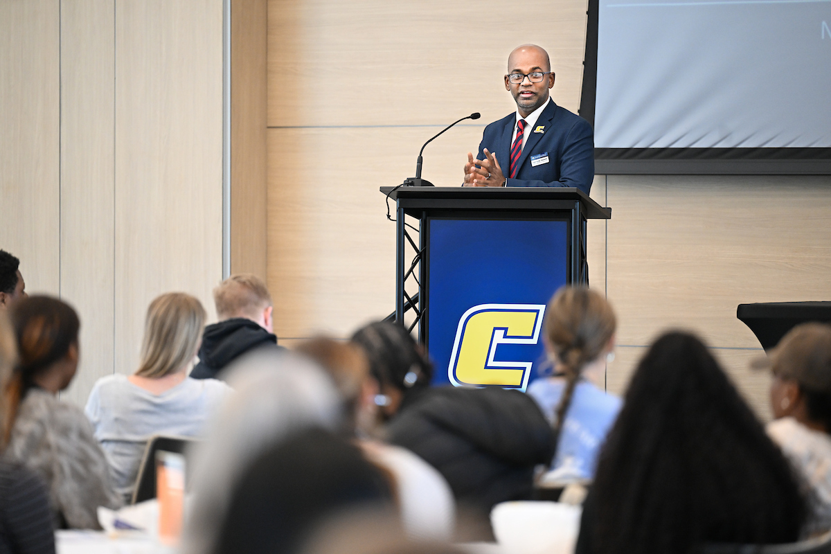 Dr. Kumar Yelamarthi speaks at a podium with a microphone during a College Quest event,