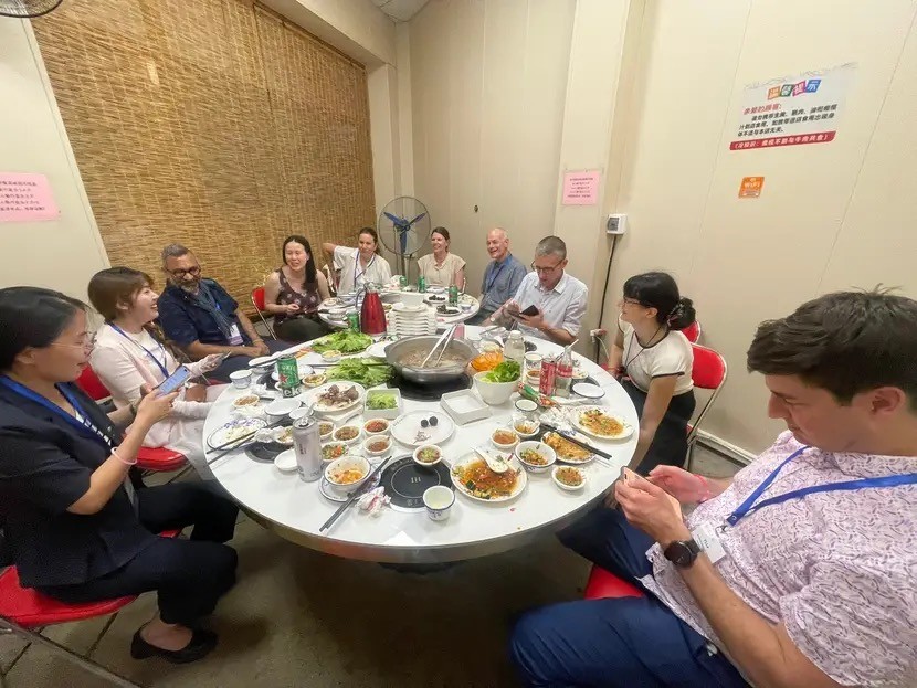 Dr. Ashleigh Pipes and fellow conference attendees sit around a large round table sharing a meal at a restaurant during the International Association for the Psychology of Language Learning conference in Shantou, China. Dishes are spread across the table as participants eat and talk together.