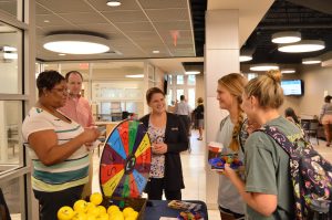 Students stand in the Decosimo Success Center, spinning a multicolored wheel.